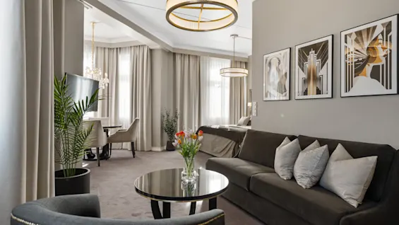 En stilfuld og komfortabel hotelsuite med opholdsstue, spiseplads og seng, indrettet med moderne design.