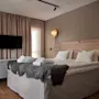 Ett modernt och inbjudande hotellrum med en stor säng, badrockar, en väggmonterad TV och varm belysning.