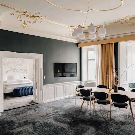 En luksuriøs hotelsuite med spiseplads og udsigt til et soveværelse, med elegant indretning og moderne møbler.