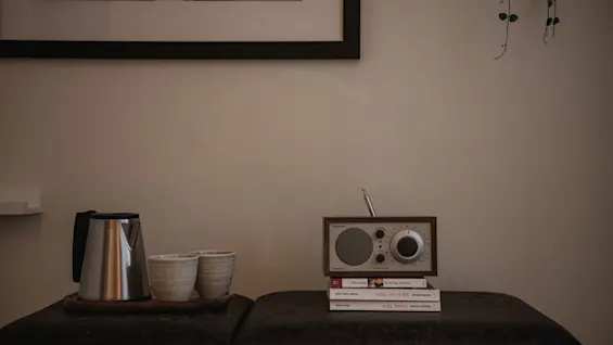 En mysig hörna i ett hotellrum på Home Hotel Grand, Helsingborg, med en vintage radio, böcker och ett teset för en avkopplande vistelse.