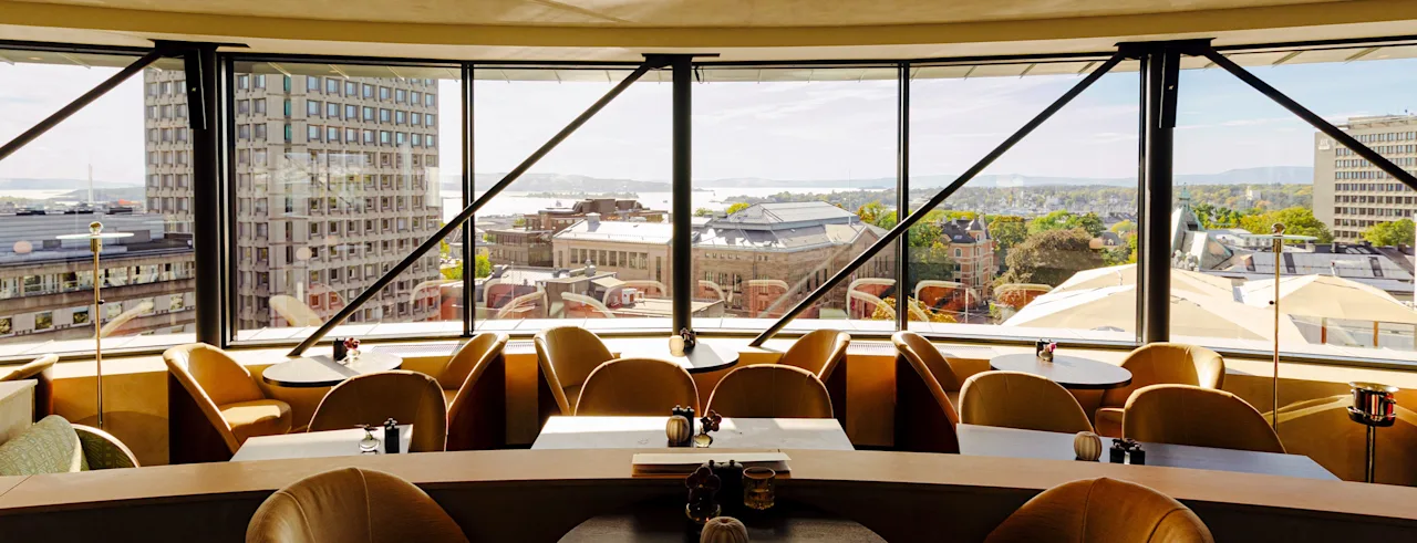 A chic interior space featuring large windows that offer a breathtaking panoramic view of a city and water.