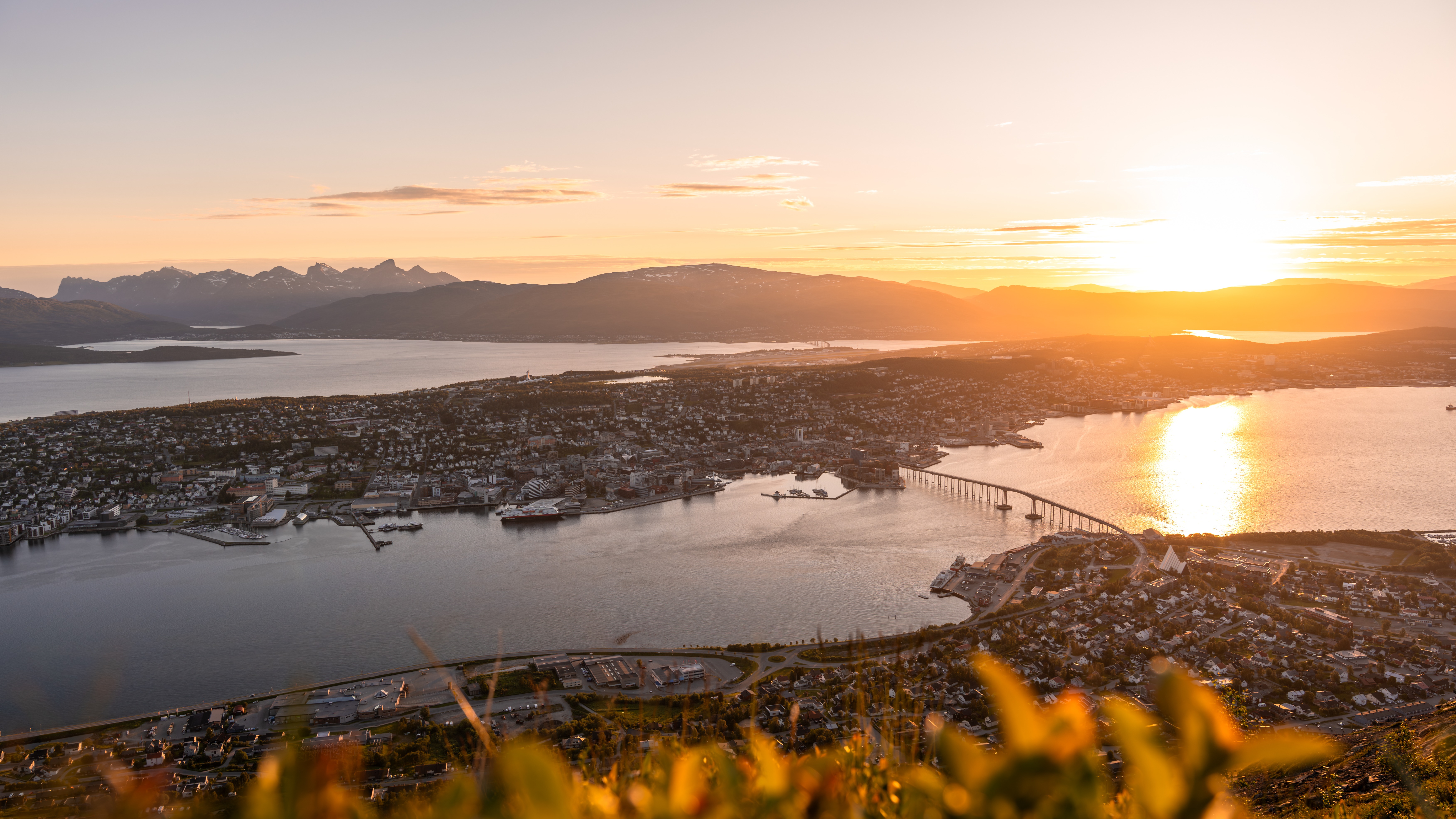 Tromso harbour and bridge glowing under the Norwegian midnight sun
