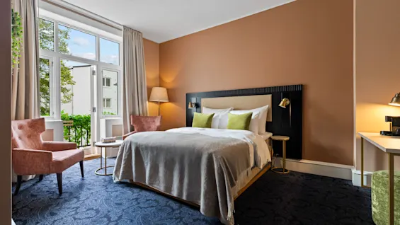 Et koselig hotellrom på Home Hotel Gabelshus med en stor seng, to lenestoler og balkongutsikt.