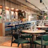 Et moderne restaurantinteriør med treaksenter, dekkede bord og grønne stoler, klart for gjester.