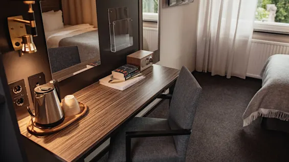Kutsuva hotellihuone, jossa on toimiva työpöytäalue, vedenkeitin ja lukumateriaalia sekä mukava sänky.