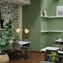 Bord och stolar är arrangerade i ett grönt väggkafé prytt med lövverkstapeter och monokrom konst. En krukväxt och mjuk belysning förstärker den välkomnande atmosfären.
