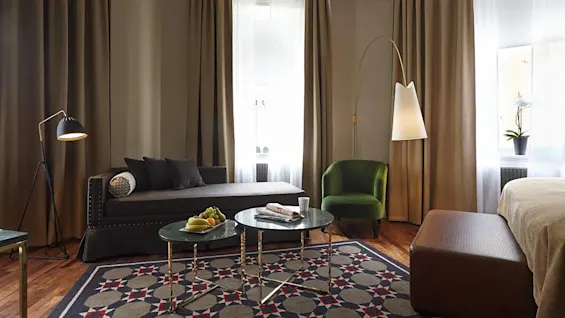 A tastefully decorated living room with a dark sofa, accentuated by a colorful rug, illuminated by floor lamps, exudes a cozy ambiance. No text present.