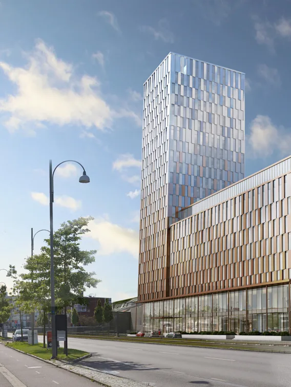 En hög, modern byggnad med reflekterande glaspaneler står på en stadsgata kantad med träd och gatubelysning. Nära finns en liknande glasbyggnad med texten "KPLASTIC" och "POC."