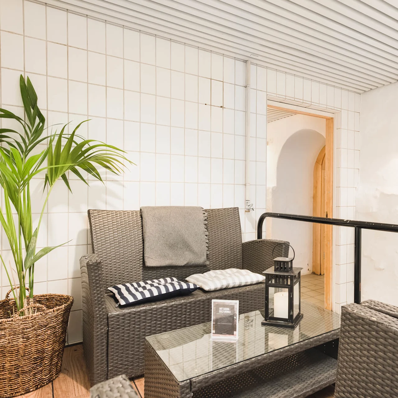 A cozy, indoor lounge area with wicker furniture and a plant, suggesting relaxation in a casual setting.