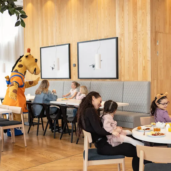 Lollo & Bernie tervehtivät lapsia aamiaispöydän luona.