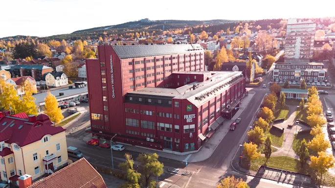 Ilmakuva syksyisestä kaupungista, jossa on punainen rakennus HOTEL SUNDSVALL ja FOLKETS HUS, keltaisten puiden ympäröimänä.