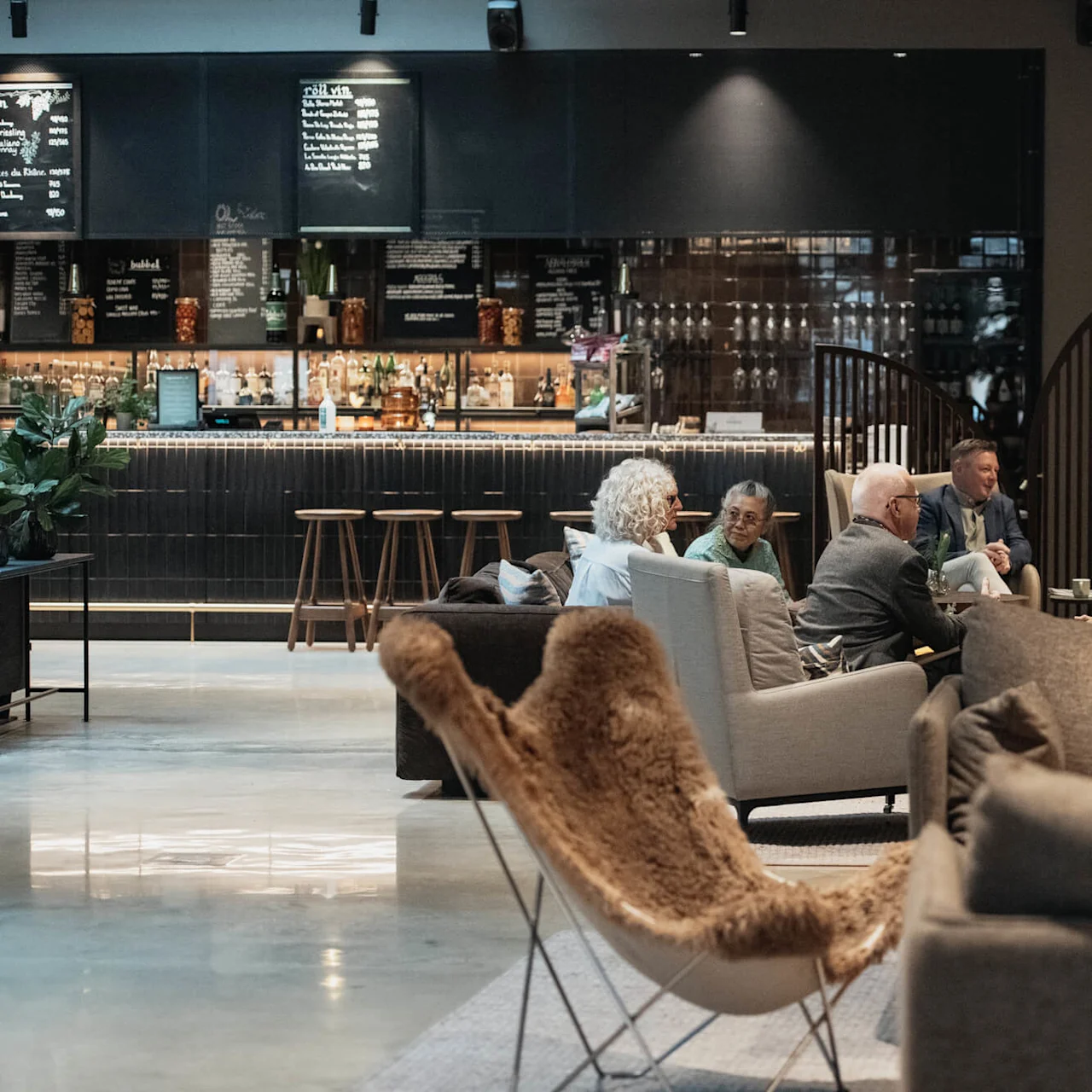 People socialize in a modern café with comfortable seating and a bar area.