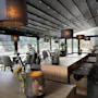 Modern covered outdoor patio with wooden tables, cozy hanging lamps, and decorative lanterns.