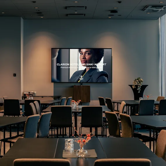 Kokoushuone Clarion Hotel Helsinki Airportissa. Näytöllä 'Hotel Helsinki Airport Premium meetings up to 1050'.