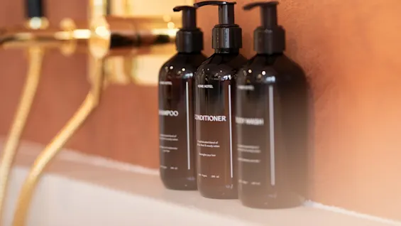 Shampoo, conditioner, and body wash bottles in a bathroom at Home Hotel Grand Bodø.