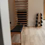 A clean and modern fitness room at Home Hotel Uppsala with an exercise bench, wall ladder, and weighted bags for a workout.
