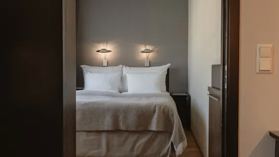 Ett mysigt hotellrum med en säng, två upplysta vägglampor och ett sängbord, som erbjuder en bekväm vistelse.