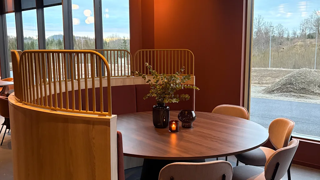 Et koselig, moderne spiseområde med et rundt bord, komfortable sitteplasser og et varmt lys fra en unik sirkulær lysarmatur.