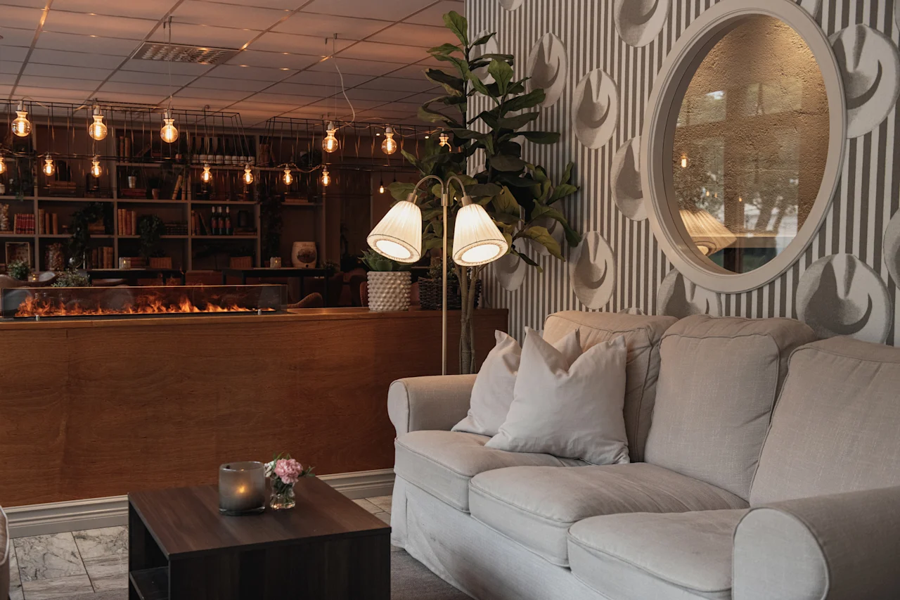 A cozy lounge area with a comfortable sofa, a warm fireplace, and bookshelves, creating an inviting atmosphere.