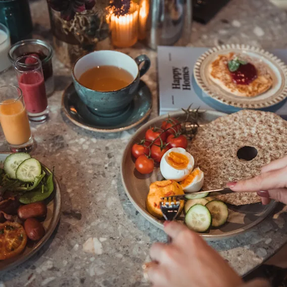 En person spiser en deilig frokost med egg, grønnsaker og te på Quality Hotel.