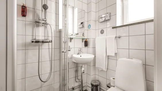 Valoisa, kaakeloitu kylpyhuone Comfort Hotel Linköping Cityssä, jossa on suihku, pesuallas, wc ja puhtaat pyyhkeet.