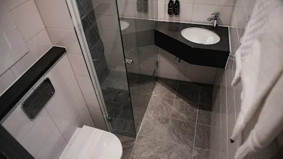 Et rent og moderne bad med toalett, en dusj med glassvegger og en elegant vask med en mørk benkeplate.