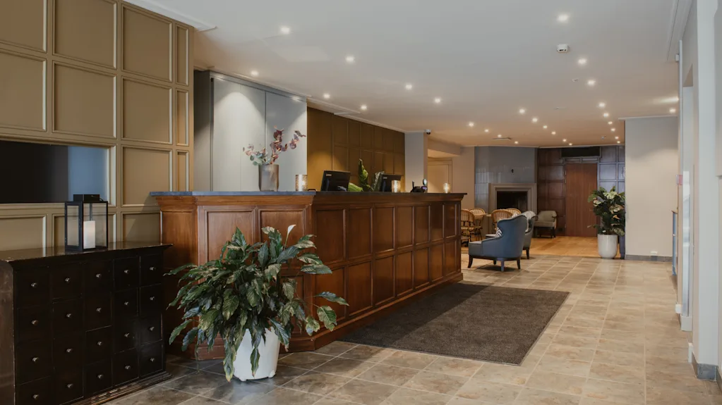 En varm og indbydende hotellobby med en reception i træ, komfortable siddepladser og en hyggelig pejs.