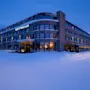Et snødekket hotell med skiltet "QUALITY HOTEL SOGN" er opplyst mot en blå skumringshimmel, omgitt av snødekte fjell og trær.