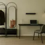 A modern room with a coat rack, mirror, and a desk with a laptop, suggesting a functional space for work or travel.
