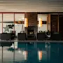 Et luksuriøst indendørs poolområde med en hyggelig lounge, pejs og store vinduer, der tilbyder en afslappende atmosfære.