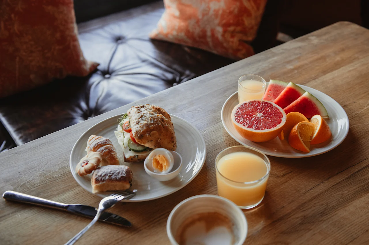 En utsökt frukostbuffé med en smörgås, bakverk, frukt och juice på ett träbord på Home Hotel Grand, Helsingborg.