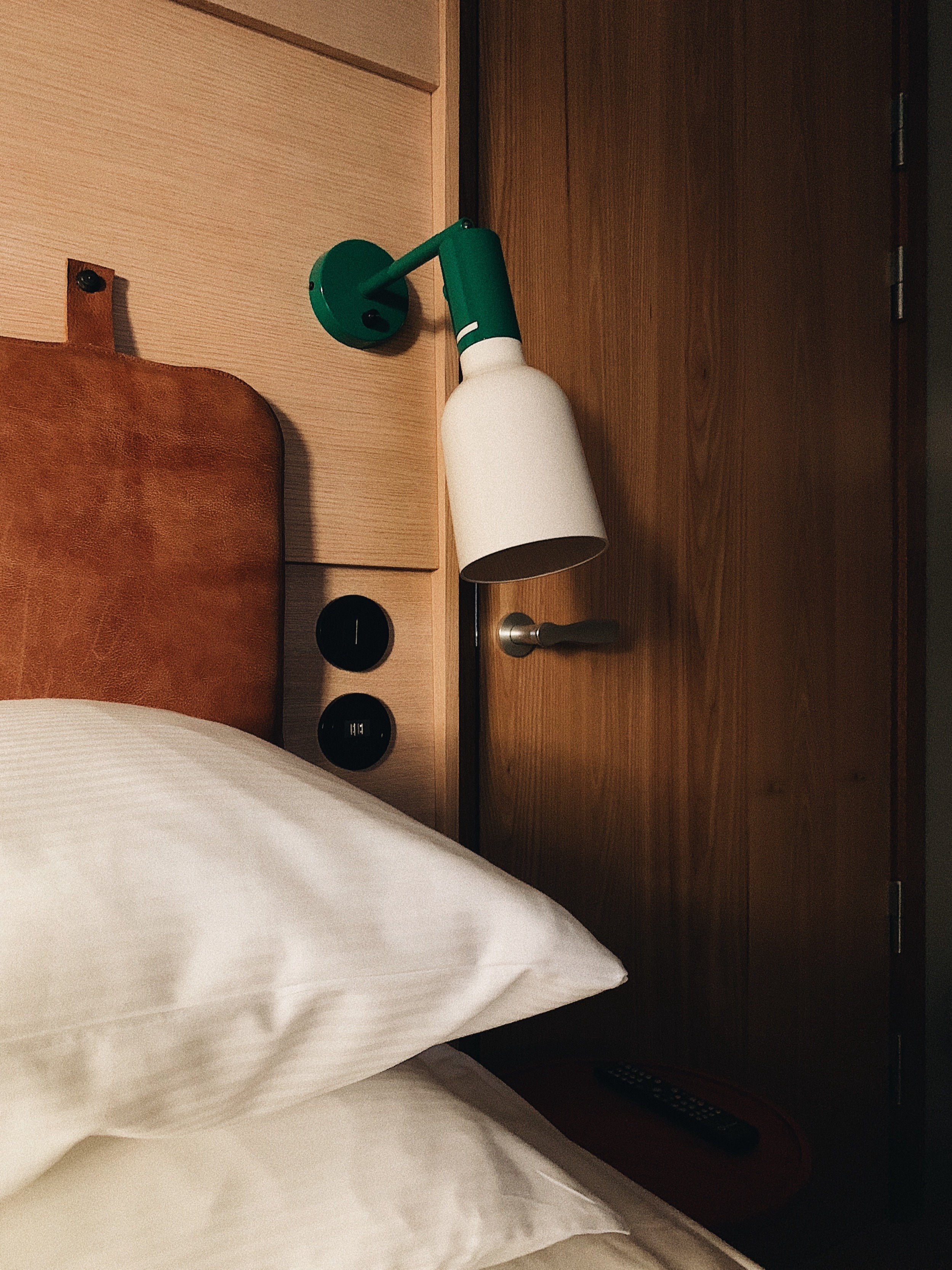 Kudde och lampa bredvid säng på hotell HOBO i Stockholm.