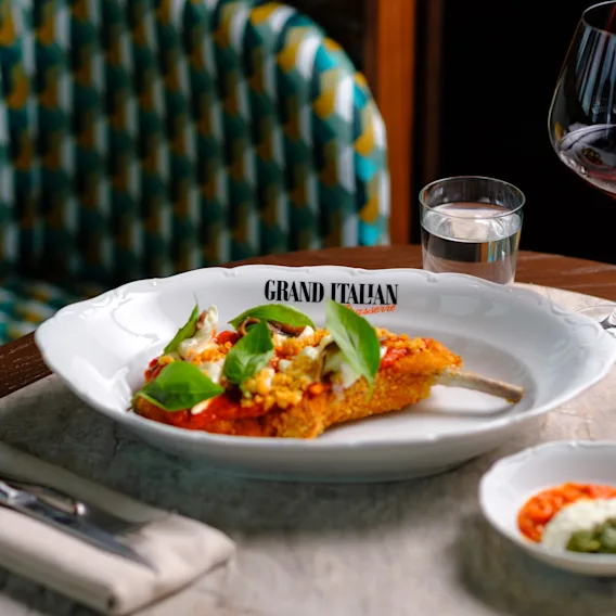 A vibrant Italian meal with a basil dish, drinks, and dipping sauces. Plate reads GRAND ITALIAN.