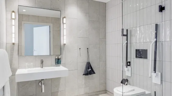 A modern bathroom interior with a sink, mirror, towel, toilet, and shower area.