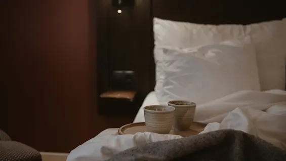 Two cozy cups on a tray on a bed with a blanket, ready for a relaxing moment at Home Hotel Kung Oscar.