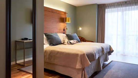 A cozy bedroom with a large bed, soft lighting, and a dog lying on the bed. It has a calm, inviting atmosphere.