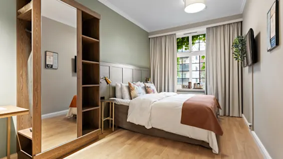 Home Hotel Gabelshus i Oslo: Et rolig soverom med en komfortabel seng, et romslig speil og vindusutsikt.