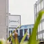 Exterior view of a modern building with a sign that reads UPPSALA HOME HOTEL, framed by green foliage.