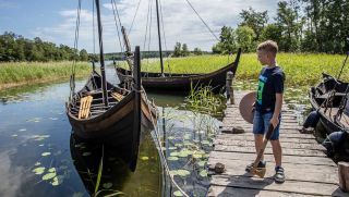 Pojke tittar på vikingaskepp på Birka. Foto: Claes Helander, Strömma Turism