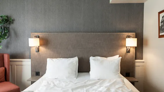 A cozy hotel bedroom at Home Hotel Grand Bodø with a comfortable bed, warm lighting, and a relaxing atmosphere.