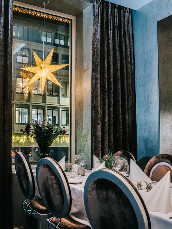 Et elegant dekket bord i en restaurant julepyntet med en lysende stjerne i vinduet.