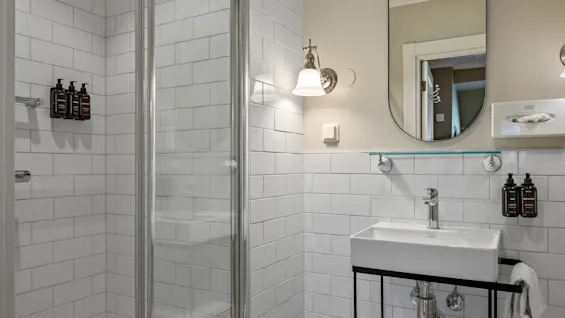 A well-lit, modern bathroom with white subway tiles, a glass shower, and a vanity area with a sink and mirror.