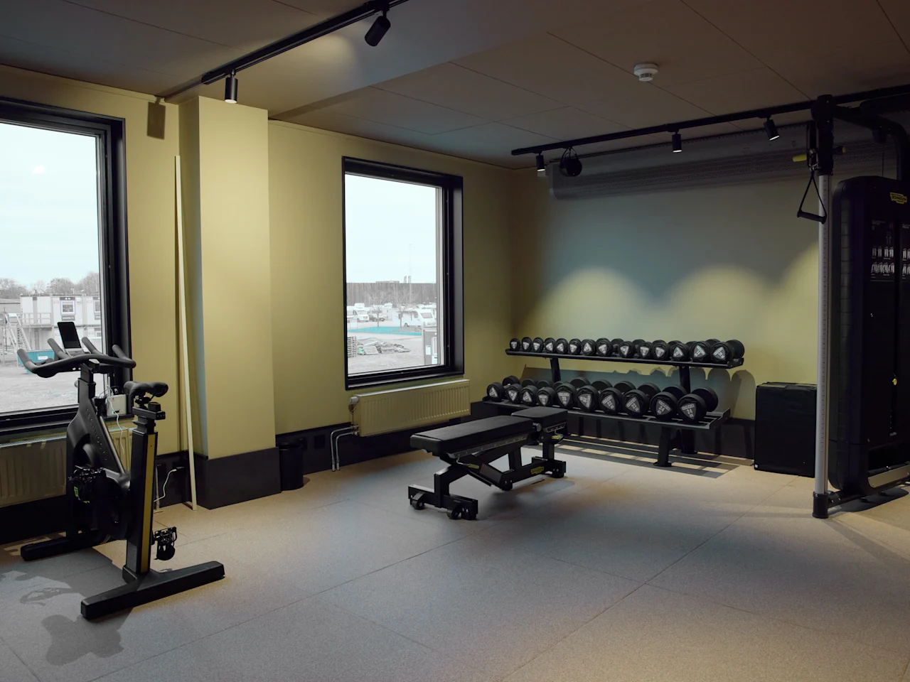 Et velutstyrt hotellgym på Stopover Hotel Falkenberg med en trimsykkel, vektbenk og manualer, klart for en treningsøkt.