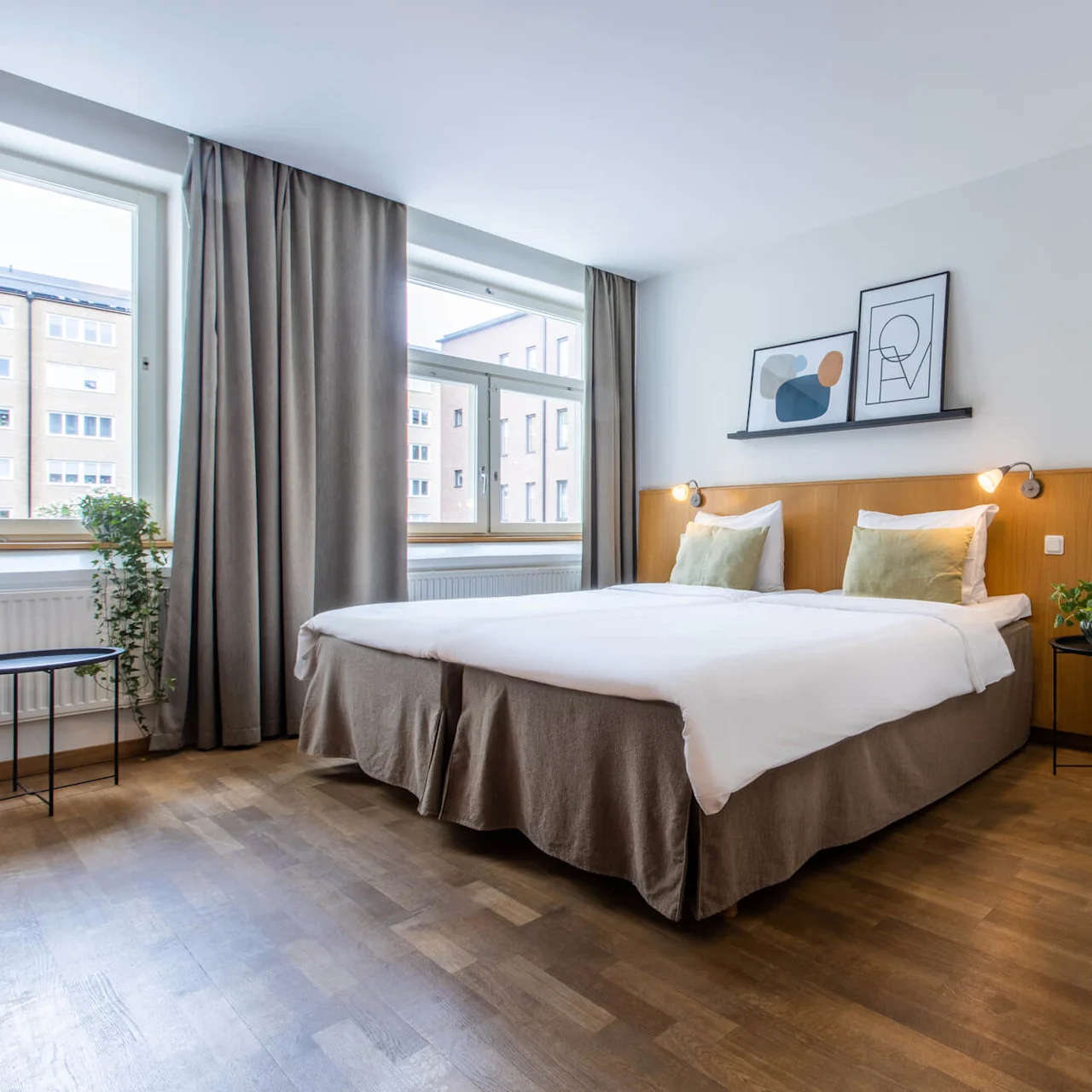 A modern bedroom with a double bed, framed art above, and wooden slats partitioning space, near a window.