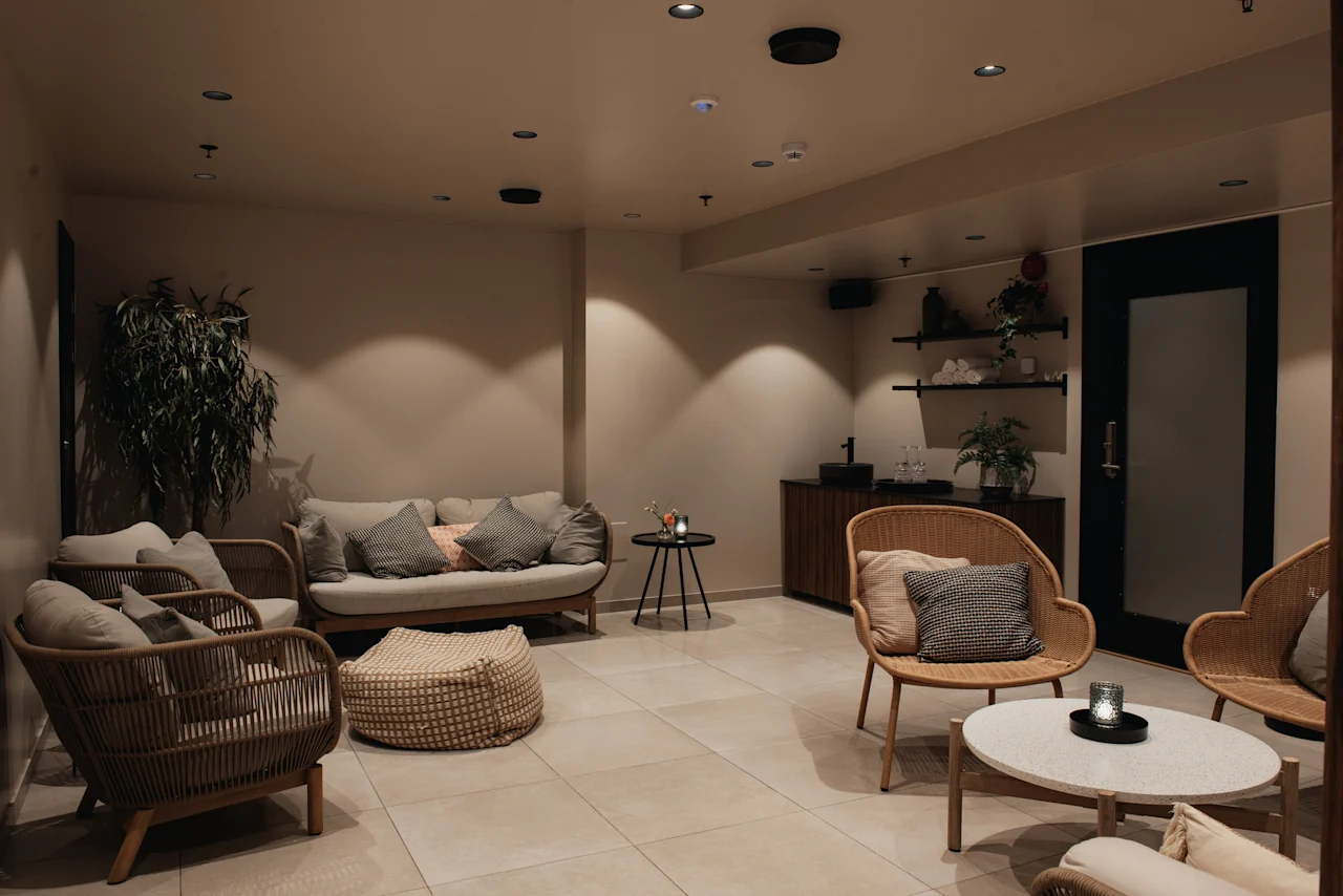 A warm and inviting lounge area at Home Hotel Uppsala with comfortable seating, a plant, and a small bar area.