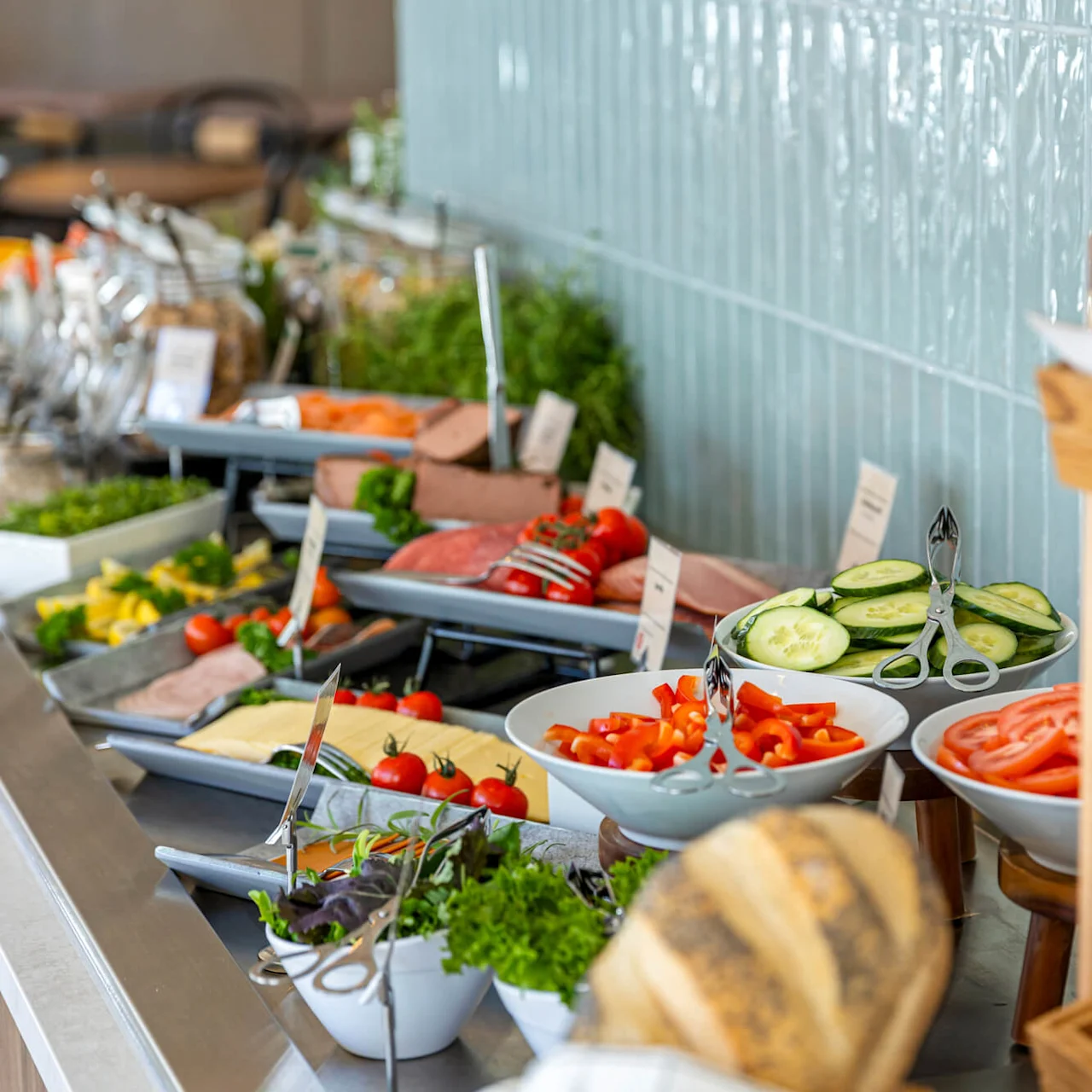 A buffet with an assortment of fresh vegetables and meats, breads on display at the side.