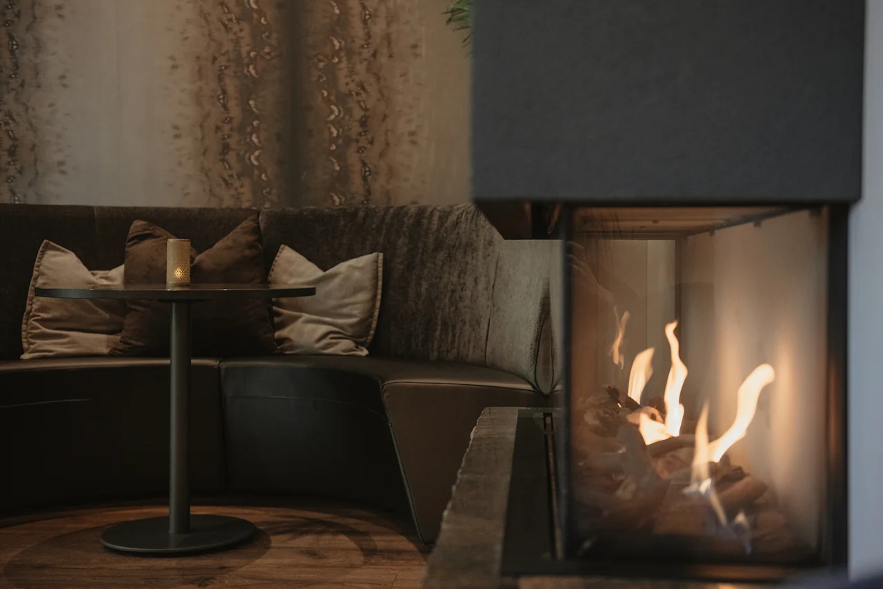 Et hyggeligt loungeområde på Home Hotel Norre Park med komfortable siddepladser, et lille bord og en varm pejs.