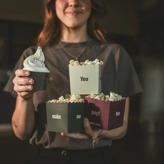En kvinna som håller en bägare mjukglass och popcornkartonger under en paus på en hotellkonferens.