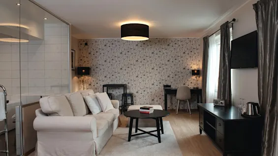 A cozy hotel room with a sofa, coffee table, and a desk area, offering a comfortable space for relaxation and work.