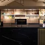 A stylish hotel reception or bar area at Home Hotel Grand Bodø, featuring a black marble counter and illuminated shelves.